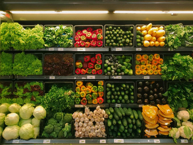 A colourful picture of different kinds of vegetables and fruits stacked on a food shelf