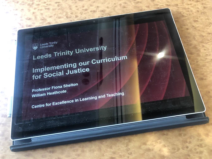 A tablet showing a PowerPoint title slide about Leeds Trinity University’s Curriculum for Social Justice implementation.