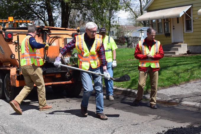 Gov. Evers holding shovel full of asphalt. 