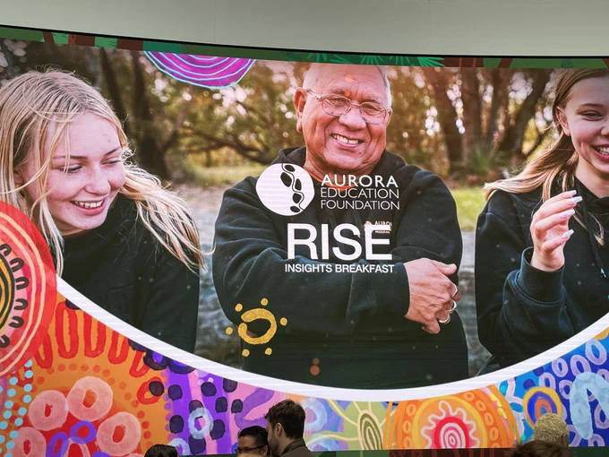 Photo of an image of three people protected on wall with the Aurora Educational Foundation logo over the top and text saying RISE insights breakfast.