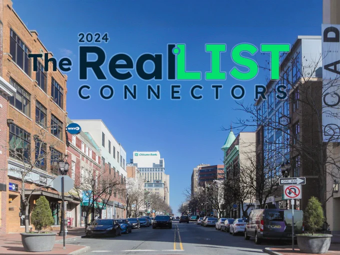 Image of a city street with parked cars, traffic signs, and modern buildings under a clear blue sky, overlaid with the text "The 2024 RealLIST Connectors."