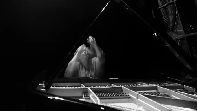 Black and white, live action, photograph of Professor Catherine Laws playing piano.