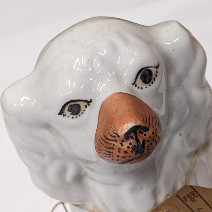 White Staffordshire dog figurine with yellow eyes and a brown nose.