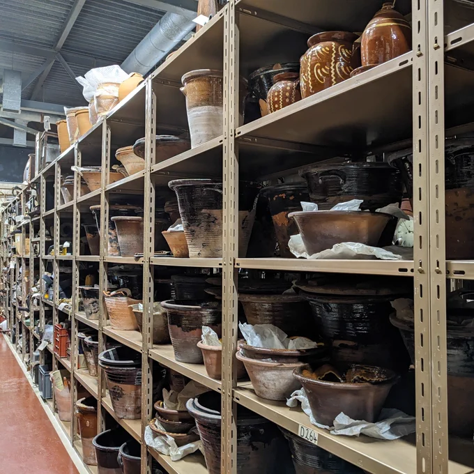 Interior of a store. Shelves filled with glazed crocks and bowls.