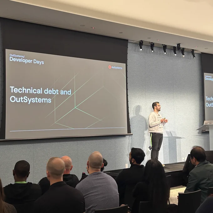 José on stage. Slide: technical debt and OutSystems