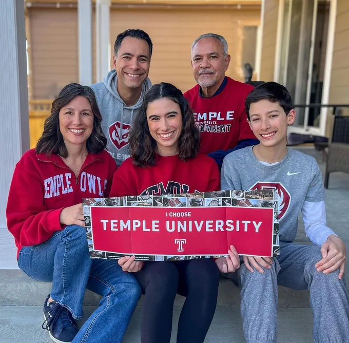 Student holding 'I Choose Temple University' sign surrounded by family.