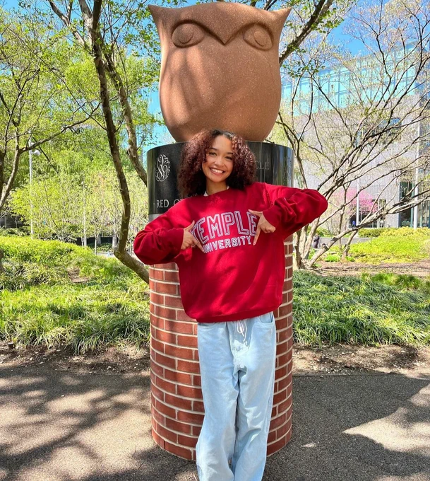 Student wearing Temple crewneck sweatshirt at the alumni owl statue. 