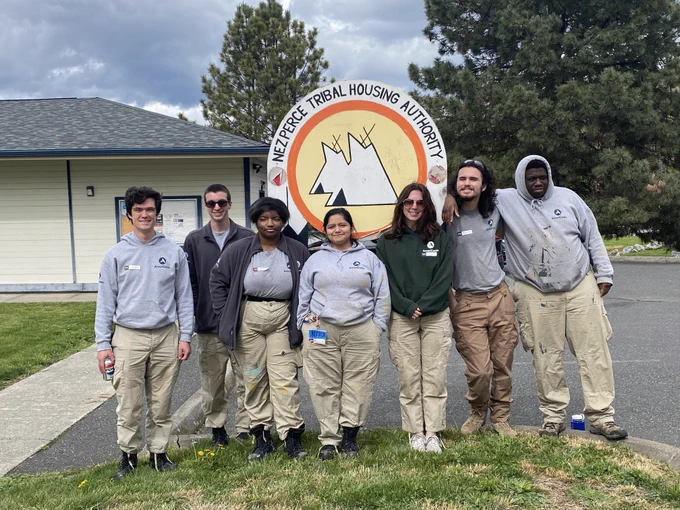 An image of AmeriCorps NCCC members posing for a group photo in front of a Nez Perce Tribal Housing Authority sign.