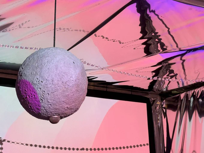 A candy coloured lit room with moons and microphones hanging from the ceiling. It's one of the zones in Sensory World. 