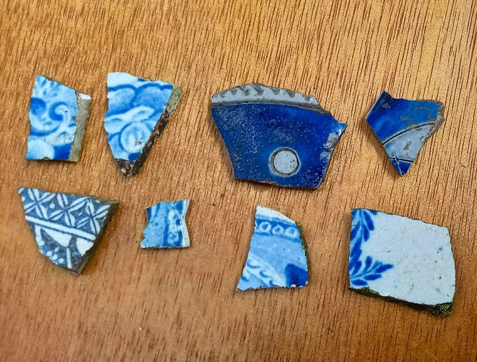 A selection of 8 blue and white ceramic fragments on a wooden table.