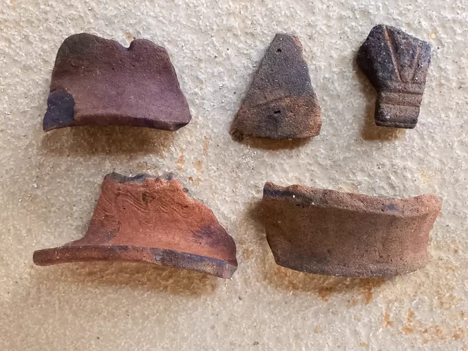 A selection of 5 warm brown coloured ceramic fragments on a cream table.