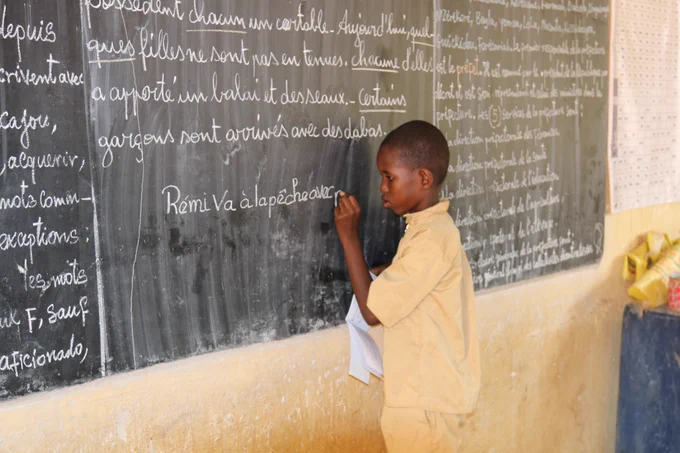 Student writes sentence on blackboard. 