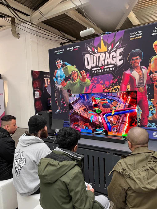 4 players sitting in front of Outrage: Fight Fest booth playing the game.