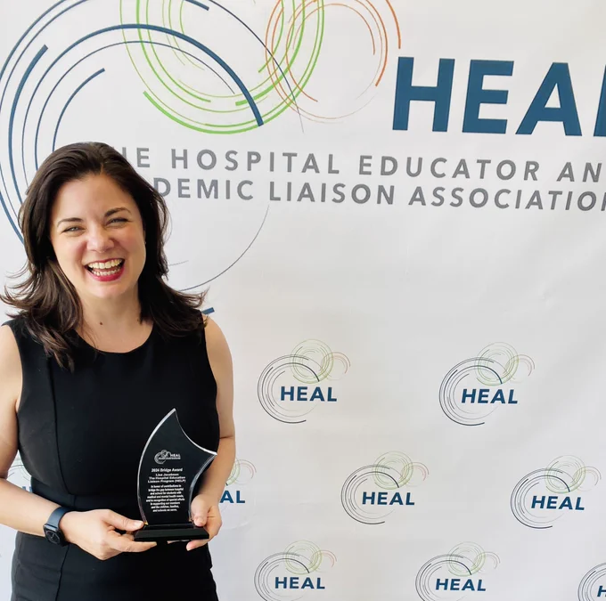 Lisa Carey stands holding the HEAL Bridge award