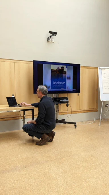 Nick Barnes in Burrell Collection room, squatting,  preparing a slide show about the book 'Working Relationally With Young People'