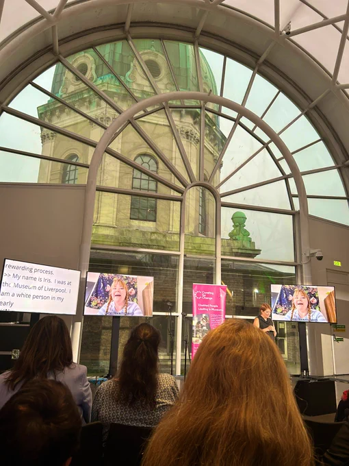Rooftop arched window in Imperial War Museum with stone building behind. Screens feature Iris Sirendi talking about her fellowship