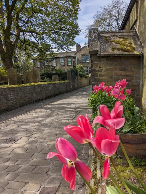 Photograph of an 18th-century parsonage on a sunny day with pink tulips in the foreground.