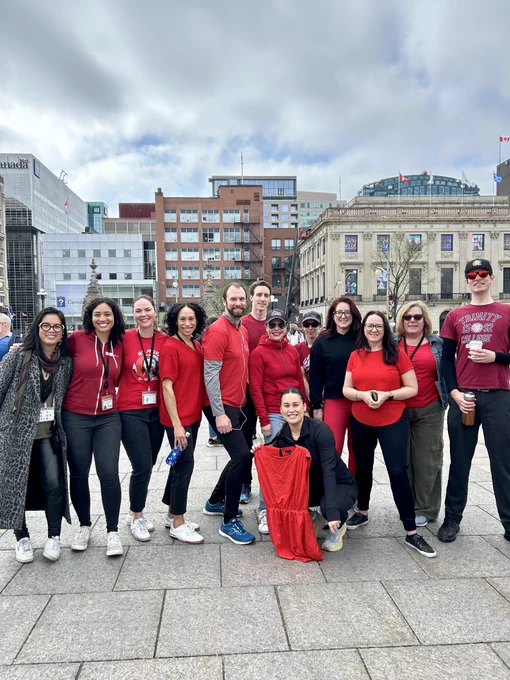 A group of employees wearing red and holding a red dress. 