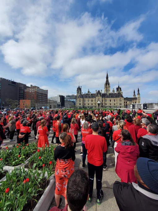 A group of employees wearing red and standing in a crowd.  