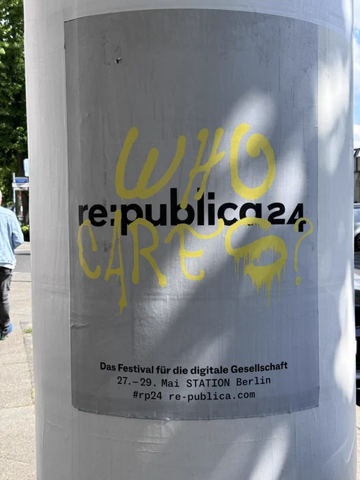 Ein Werbeplakat auf einer Berliner Litfaßsäule. Aufschrift: »re:publica24 - Das Festival für die digitale Gesellschaft«, darüber mit gelber Farbe aus einer Spraydose: »WHO CARES?«