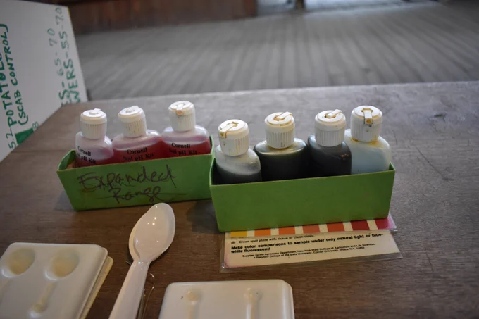 Eight small chemical bottles in two boxes with a plastic spoon and testing kit.