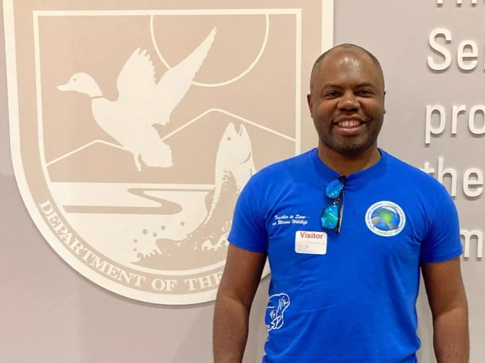 Dr. Aristide Kamla standing in front of the u.s. fish and wildlife service sign