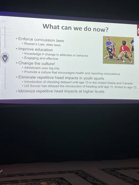 On a large screen a slide that is titled 'What can we do know' is projected to a ballroom full of International Concussion Summit delegates.