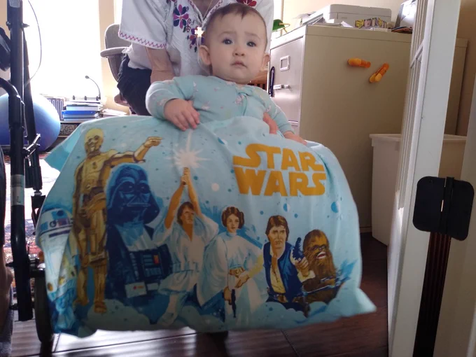 Ember, an almost 1 year old baby girl with brown hair blue eyes with a blue original Star Wars pillowcase. Her parents tried for 10 heartbreaking years to have a baby before she finally found them. #IVFbaby