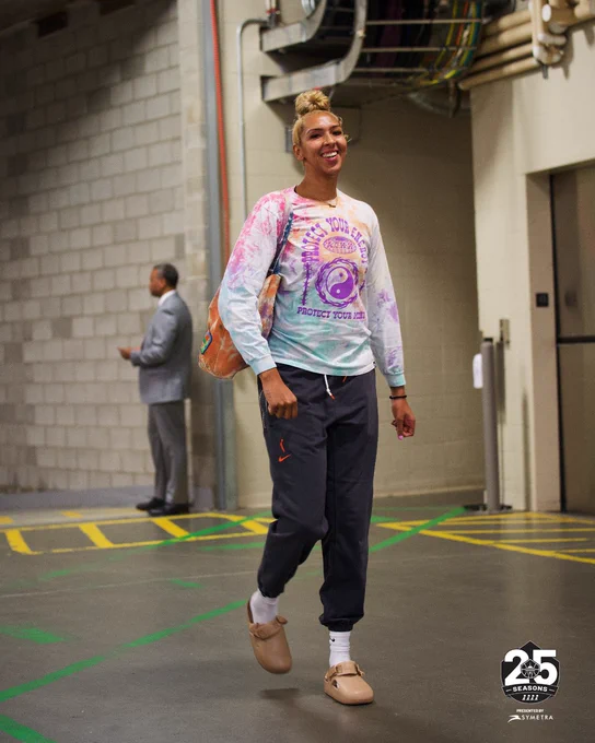 Mercedes Russell in a long sleeved tie-dye shirt and black sweatpants walking through the loading dock at Rogers Place