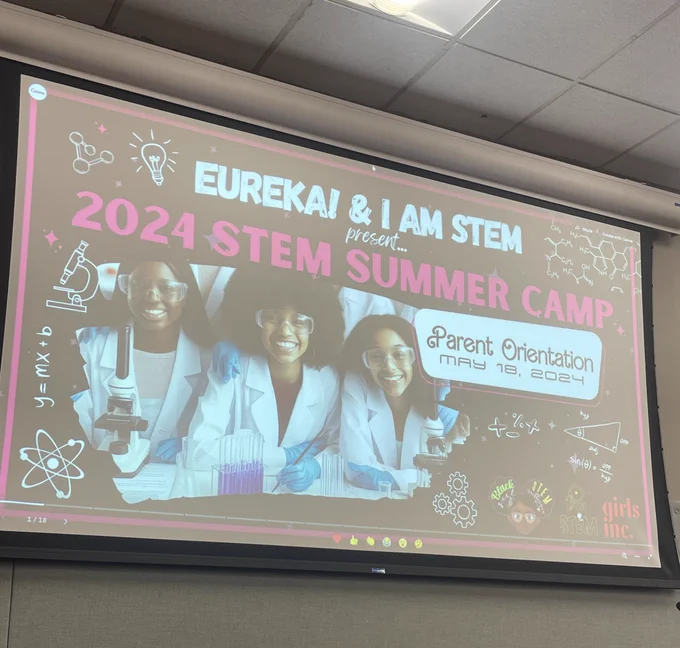 Photo of a parent orientation presentation set up. Presentation slide features three joyful Black girls in a science lab with the title “2024 STEM Summer Camp”
