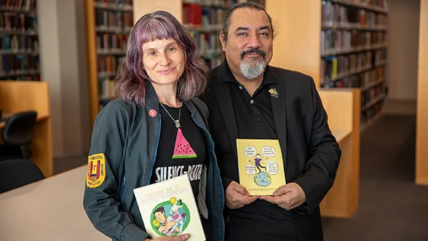 Annabelle Heckler and Sandy Jimenez with “Comics as a Second Language,” which they co-authored with fellow students in a new graphic memoir class. (Photo by Alex Irklievski)