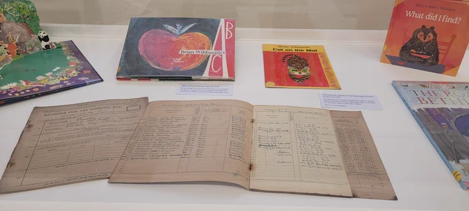 Books arranged in a display case, at the front is an attendance register from Barnsley Art School