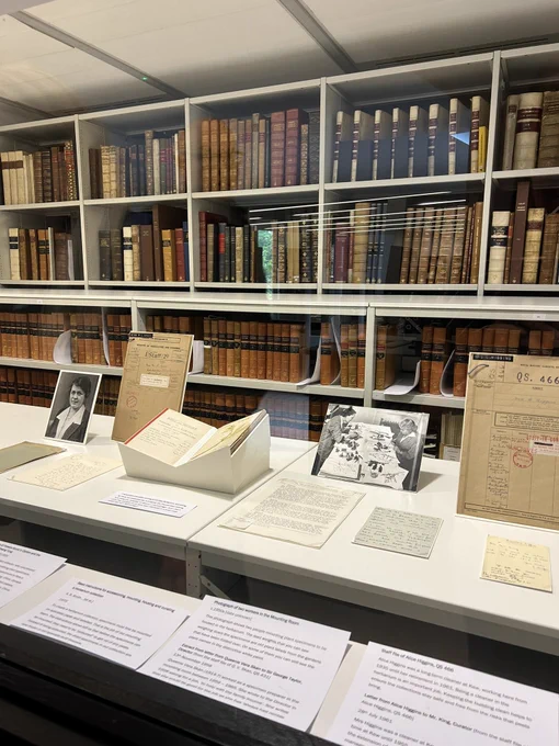 Looking through another section of a window at another section of the display. Here we see archival documents alongside photographs. Again there are rows and rows of older looking books in the background.