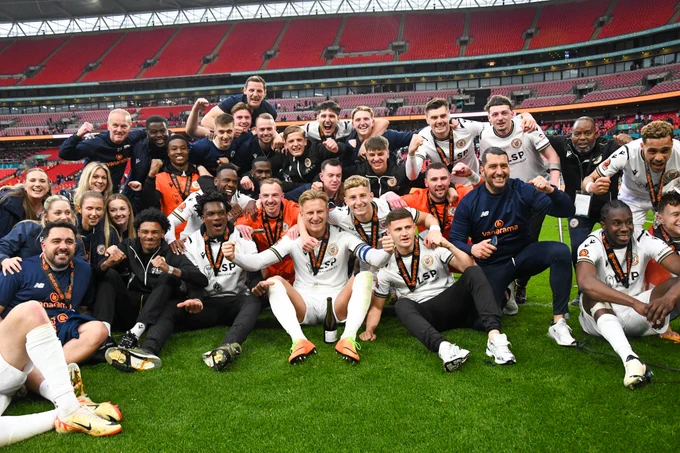 Photo of Bromley FC players celebrating on the pitch at Wembley.
