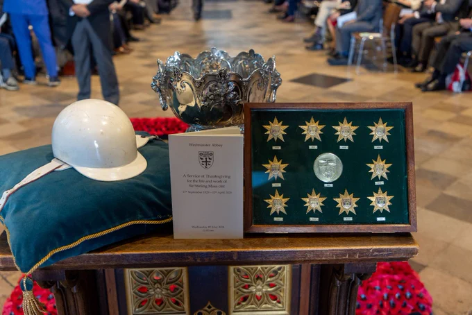 Sir Stirling Moss's racing helmet, a trophy and framed racing stars on a table in Westminster Abbey