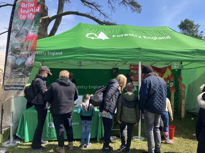 This image shows a Forestry England tent at an event with people looking at the displays within it and talking to Forestry England staff. 