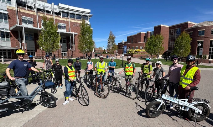 about 15 people standing next to bikes on a plaza in front of the Joe Crawley Student Union on the University of Nevada, Reno campus.