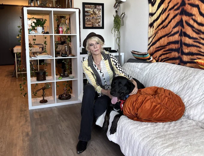 A woman sits with her dog in her apartment.