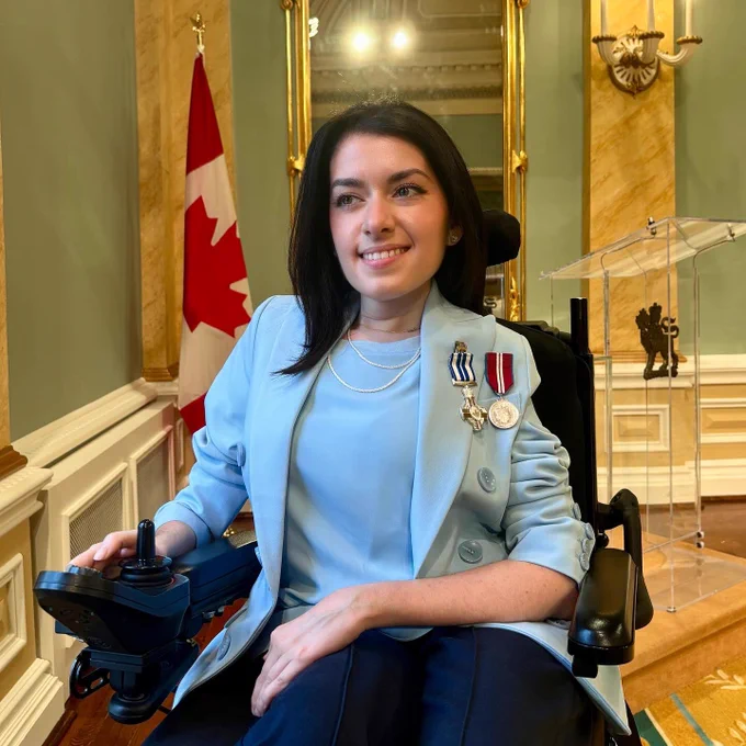 Maayan Ziv smiles wearing two medals. Behind her is Rideau hall grand room and the canada flag.