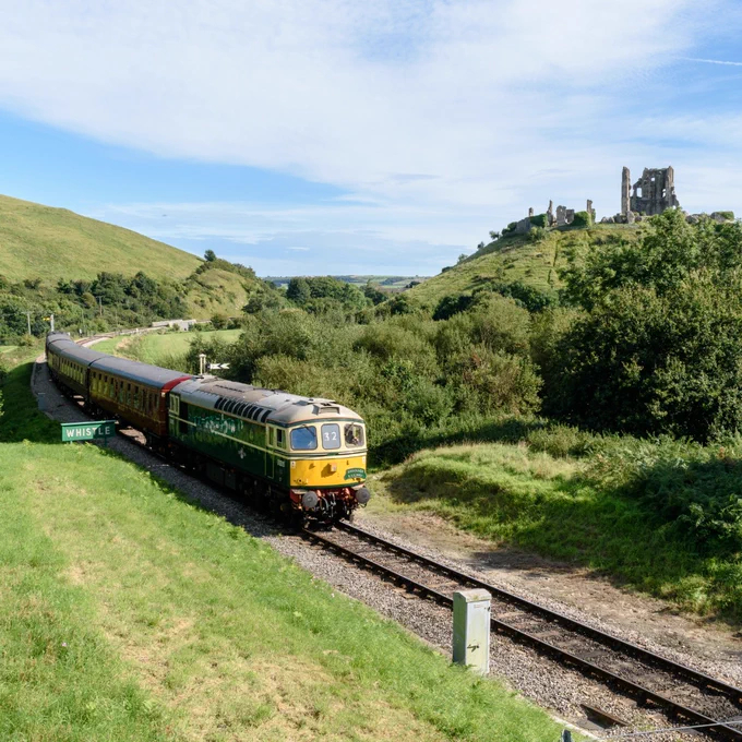 a train traveling down train tracks surrounded by rolling green hills on a sunny day