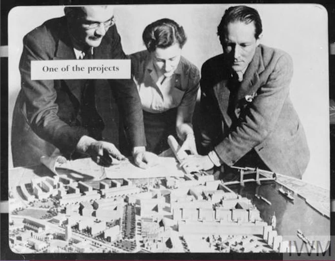 post-war planners and architects, two men and one woman, looking over a modernist architectural model of London, with the caption 'One of the projects' pasted over the top