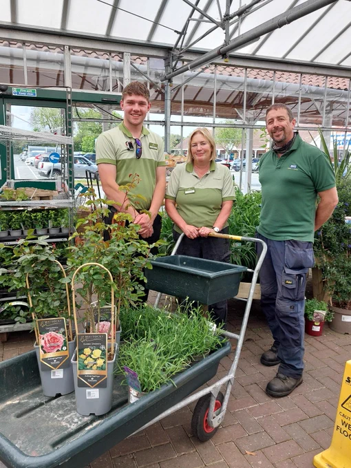 Three members of Notcutts staff stand with a trolley laden with flowers and plants to be donated to BCHC Charity