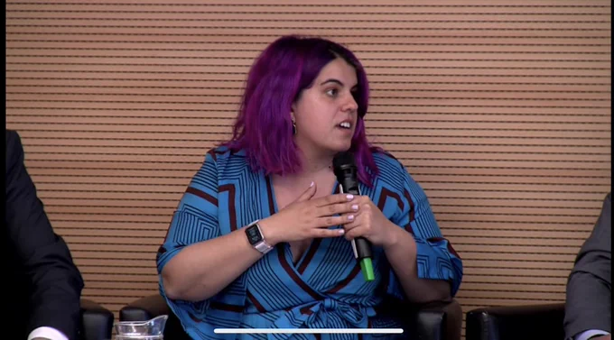 Primer plano de mi intervención. Llevo un micrófono y un vestido azul. Estoy mirando de perfil