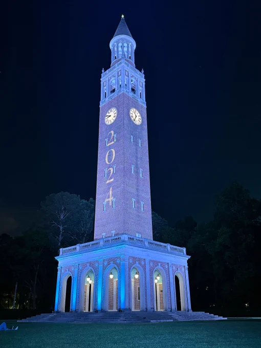 a photo of UNC's bell tower lit up in Carolina Blue to celebrate the graduating class of 2024. 