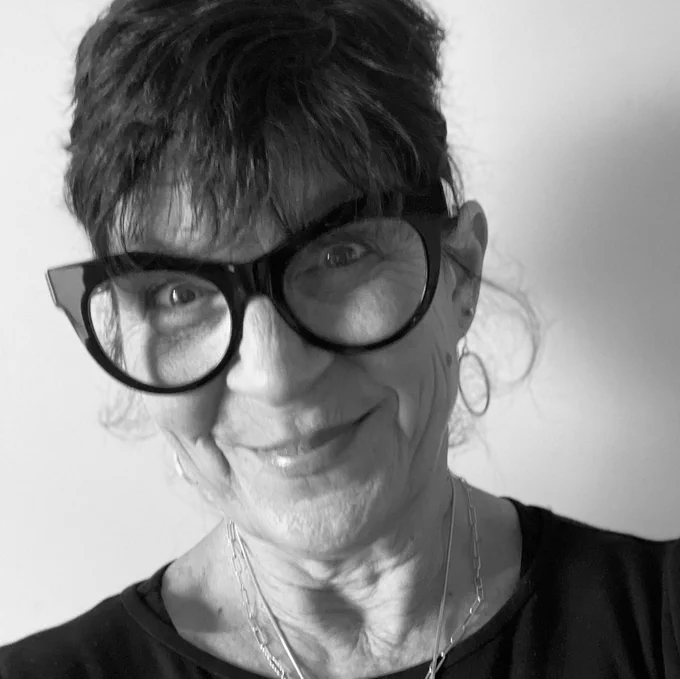 Black and white headshot of Catherine Cronin, a woman wearing dark glasses