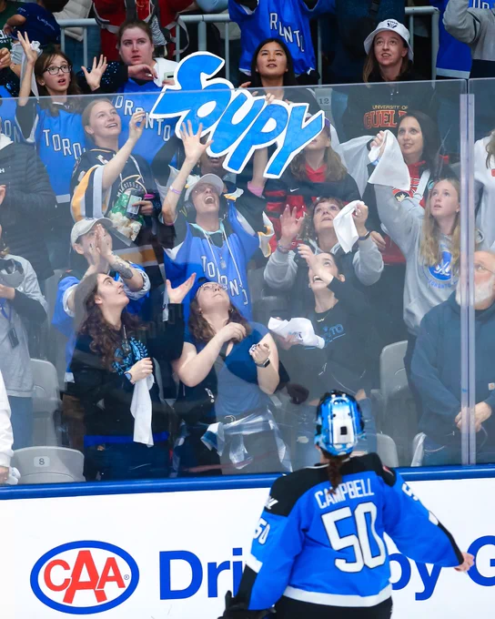 Kristen Campbell giving fans with a “Soupy” sign a puck.