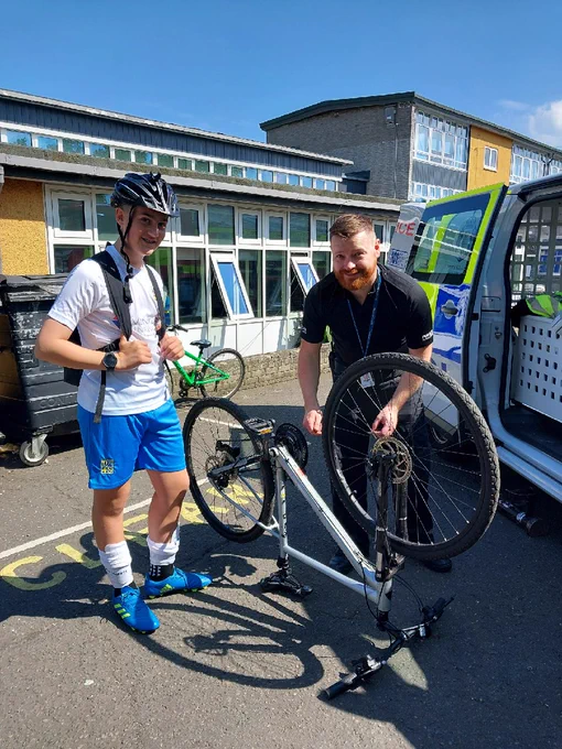 Image shows two males next to a white pedal cycle. One of the males is a Police Officer who is marking the pedal cycle with a security tag. The other male is wearing a cycle helmet