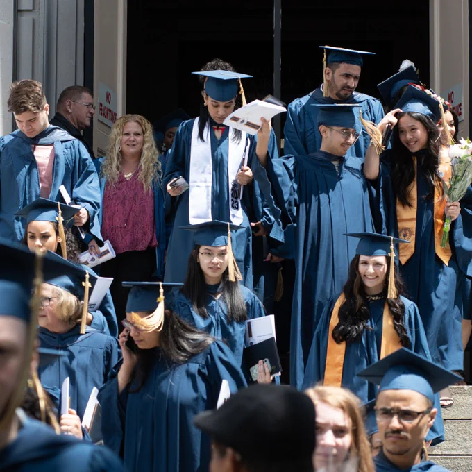 people in caps and gowns stand outside