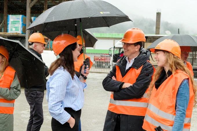 Bas Eickhout talking to a woman from a sustainable construction company, wearing an orange safety west and helmet.