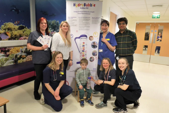 Ivan Wright, a Cystic Fibrosis patient, pictured with the HydroBubble device with Mum Rebecca Bott (back row, second from left) and members of the cystic fibrosis service team.